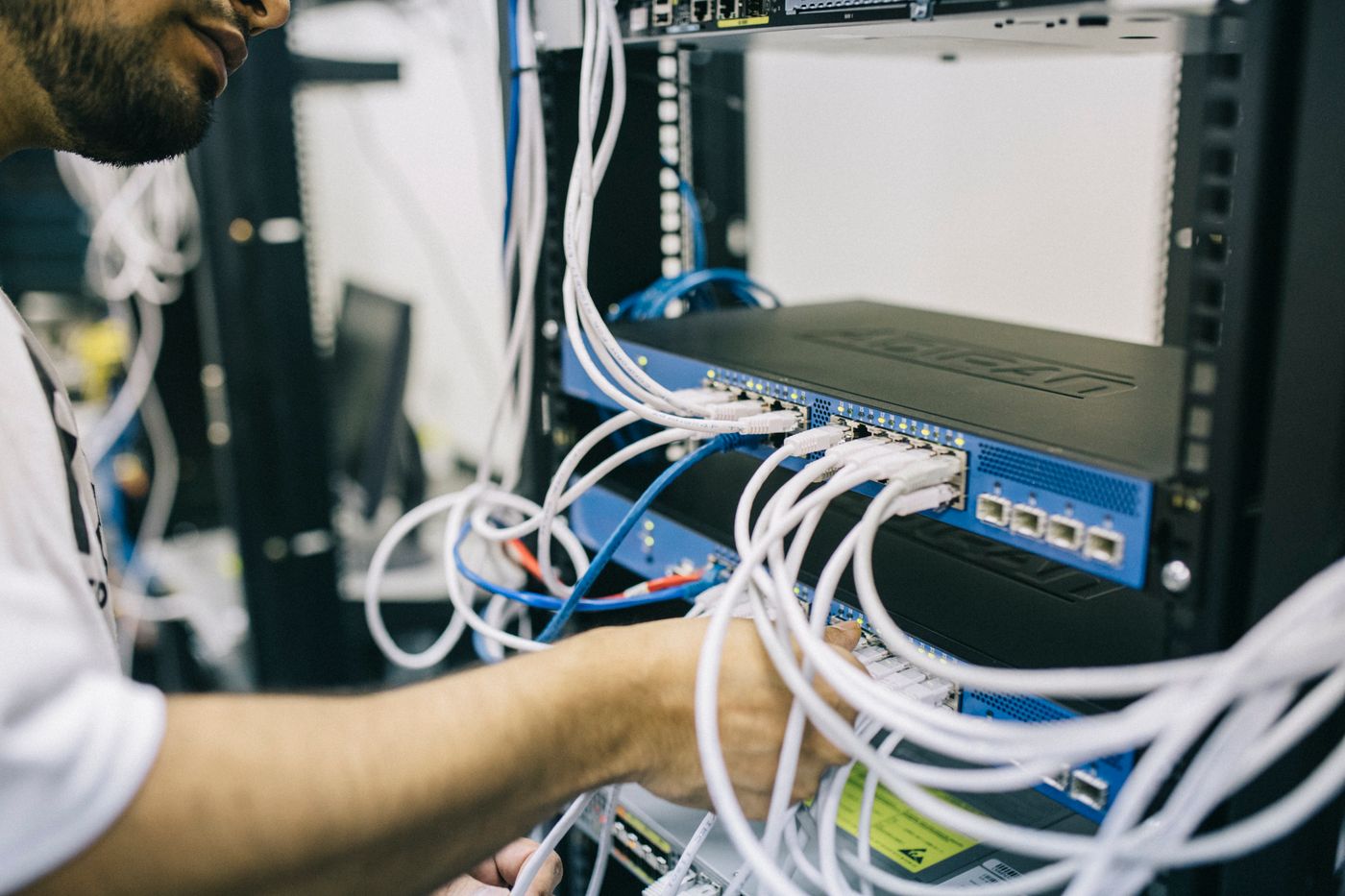 Un technicien branche des câbles réseau dans la baie informatique d’une entreprise