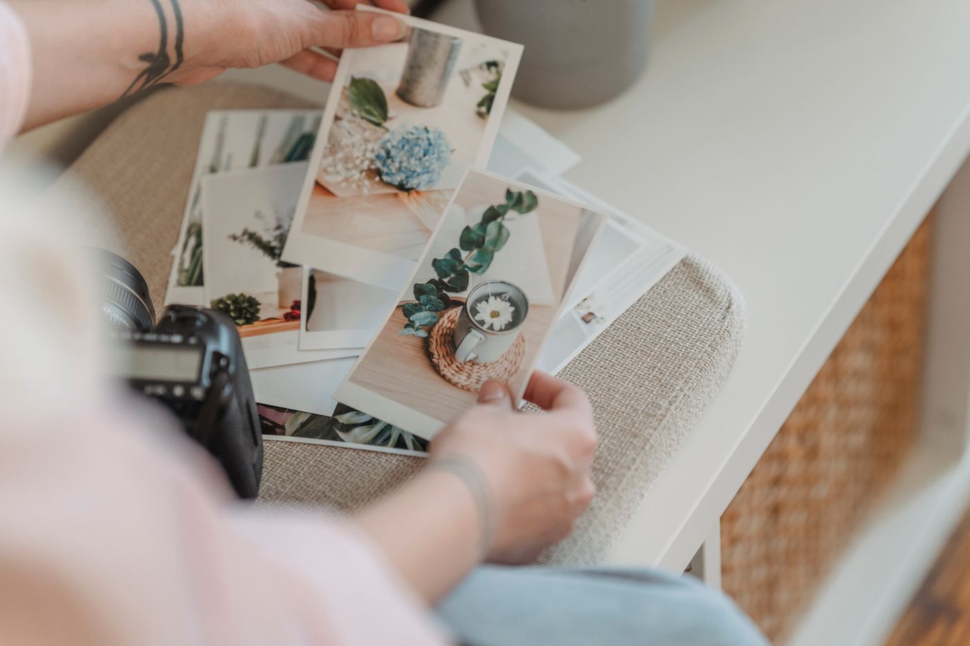Des tirages photo étalés sur une table, triés à la main à côté d’un appareil photo
